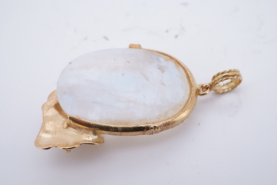 A gold and moonstone pendant, set with a moonstone cabochon, to a textured gold mount of foliate design accented with a collet-set circular-cut ruby, length 4.5cm, gross weight approximately 12 grams